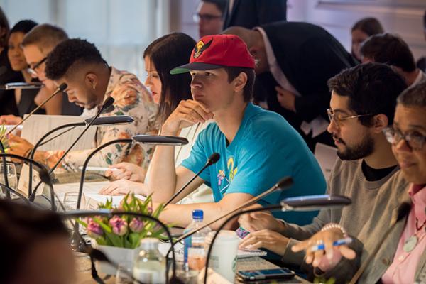 Screenwriters, directors, and actors, including Ansel Elgort (in red cap), critique the work of Ghetto Film School students. 