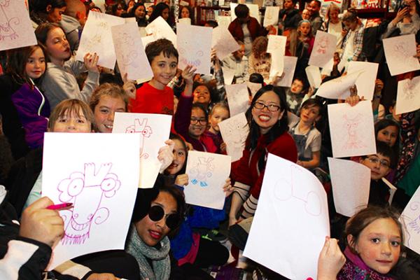 Young fans of Grace Lin hold up their dragon drawings at a book-signing event in Dedham, Massachusetts.