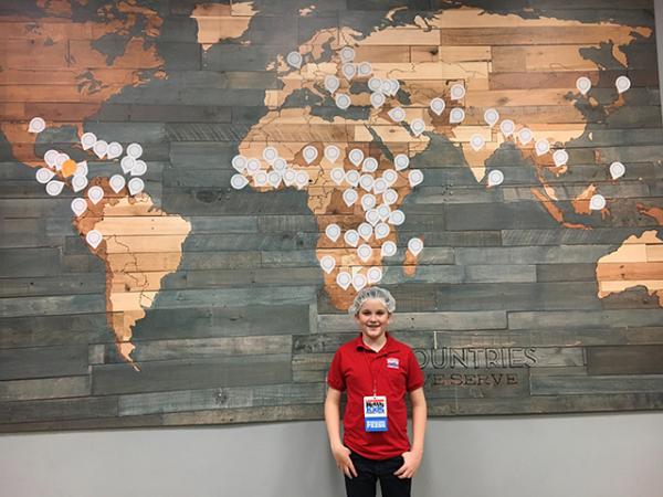 Ryan in front of a map of countries served by Feed My Starving Children