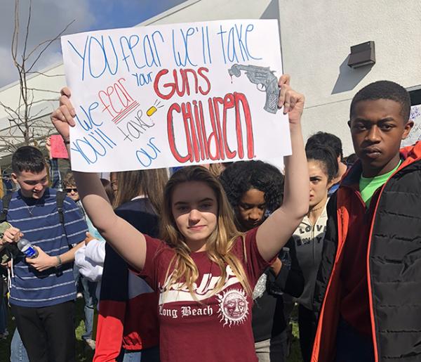 16-year-old sophomore Haley Gilson stands with a poster, expressing her views on gun control
