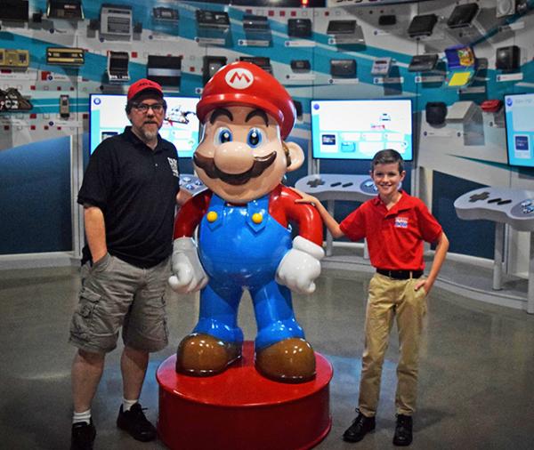 Preston Phillips and NVM co-founder, Joe Santulli, pose with Mario in the "Timeline of Consoles" room.