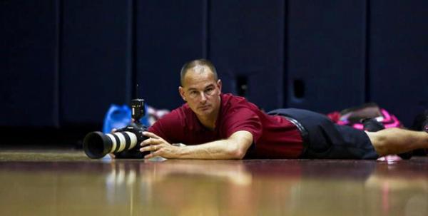 Josefczyk sprawled on the floor with his equipment to get a great shot at a basketball game.