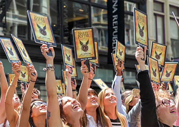 Scholastic “Muggle Mob” participants raise their paddles as the banner announcing the new Harry Potter story is lowered.