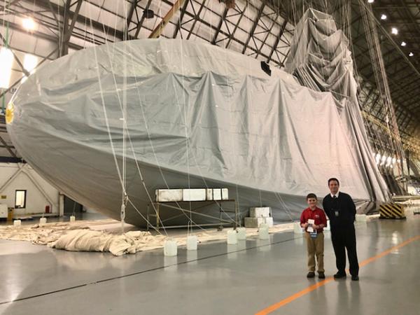 Nolan and senior pilot James Kosmos Jr. stand in front of a Goodyear Blimp currently under construction in Mogadore, Ohio.