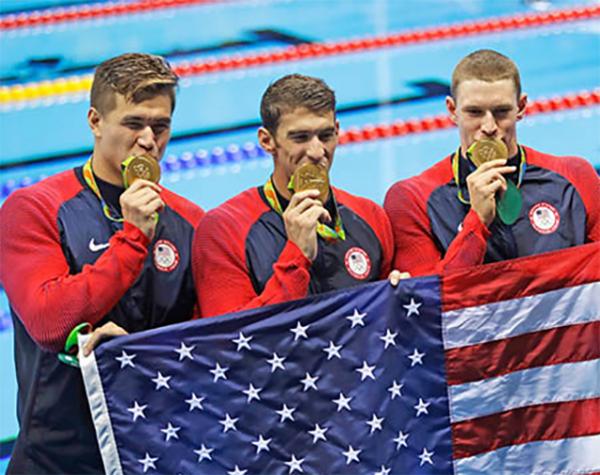Nathan Adrian, Michael Phelps, and Ryan Murphy display their gold medals during a victory lap after winning gold in the 4 x 100-meter medley relay final, the last men's swimming competition at the 2016 Summer Olympics.
