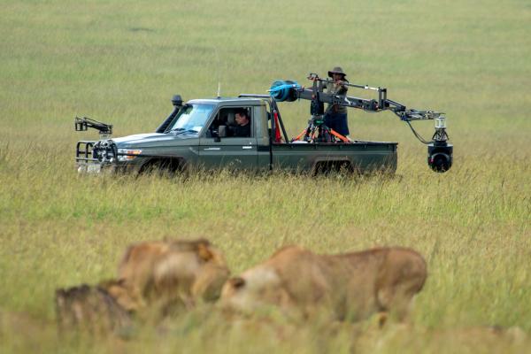 Faith Musembi stands in the back of the film vehicle, swinging the jib of the GSS camera as the crew captures Summer's Pride in action in the foreground. 