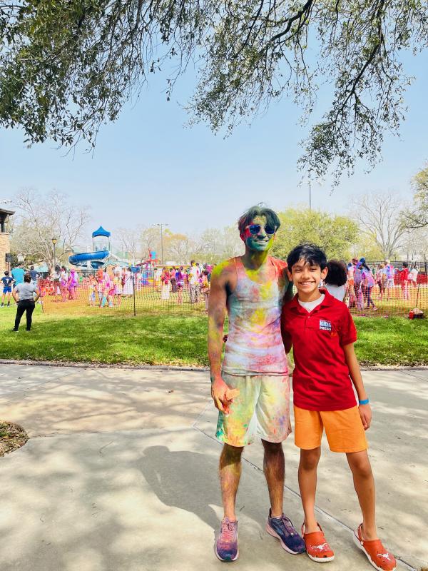 Kush stands with Shaan as a splash of color flies behind them. Kush stands with Shaan as a splash of color flies behind them.