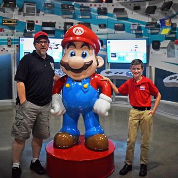 Preston and the museum co-founder, Joe Santulli, pose with Mario in the "Timeline of Consoles" room.